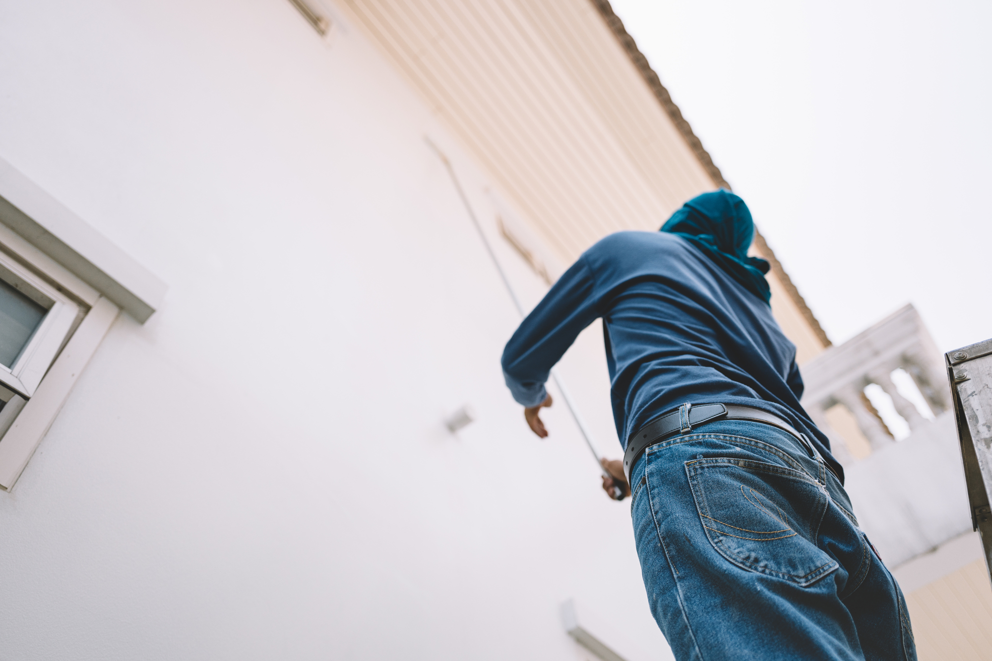 Person painting house wall from ladder outside