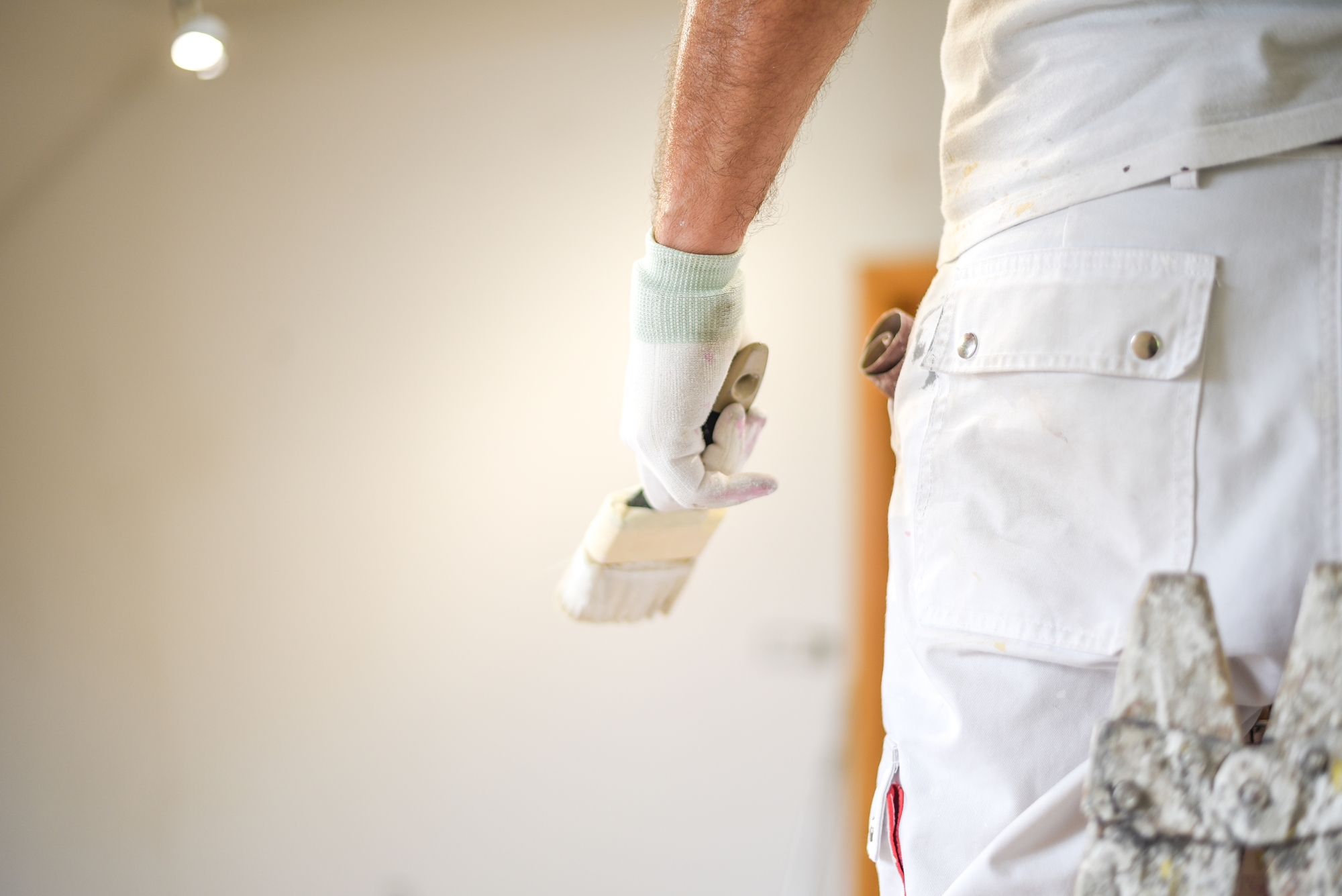 Painter holding brush, wearing white work clothes.