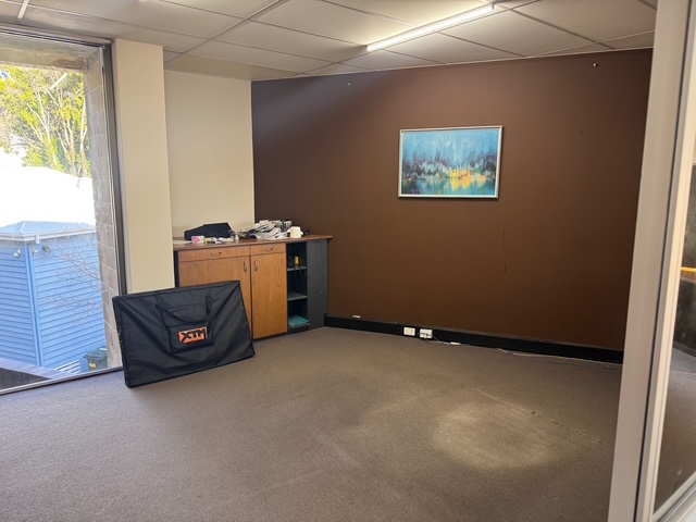 Empty office room with cabinet and wall art.
