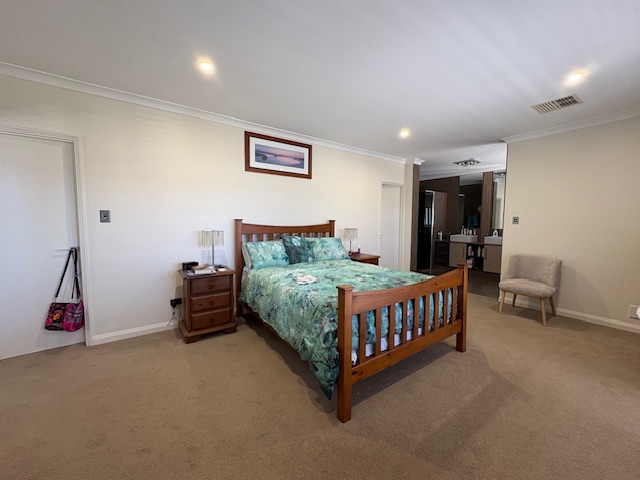 Spacious bedroom with wooden bed and green bedding.