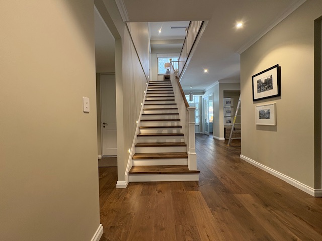 Modern hallway with wooden staircase and decor paintings.
