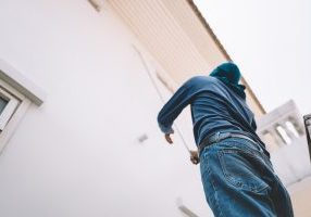 How Much Do Painters Charge to Paint the Exterior of the House? Person painting house wall from ladder outside